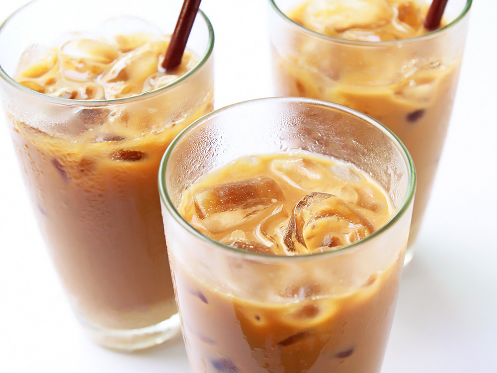 Splash of iced coffee in tall glass and coffee beans. Stock Photo