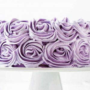 Ube cake with purple ube halaya frosting rosettes on white cake stand