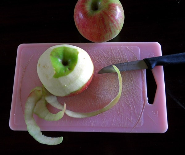 peeled apple on pink cutting board