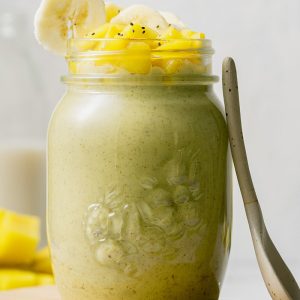Mango Banana Avocado Smoothie in glass drinking jar with mango cubes and banana slices as topping