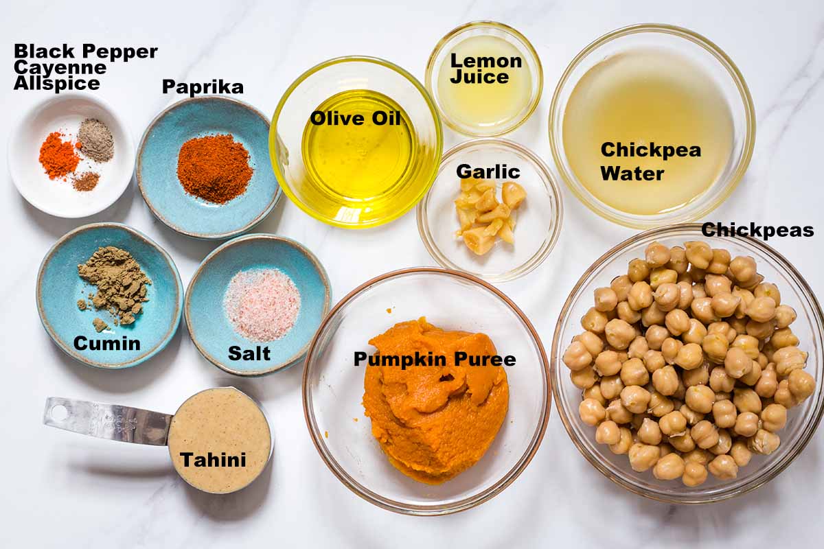 Ingredients for pumpkin hummus in individual bowls in a flat lay