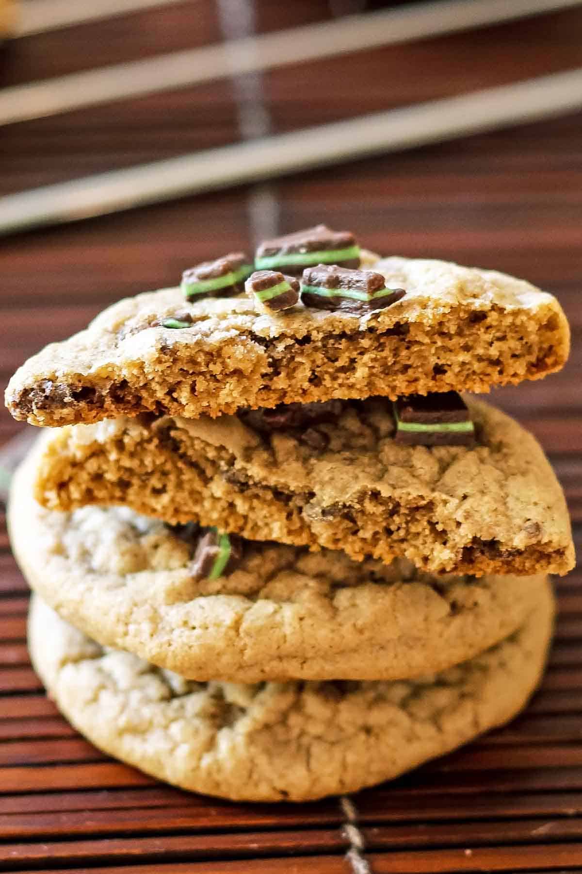 stack of mint chocolate chip cookies one is broken in half to reveal inside texture
