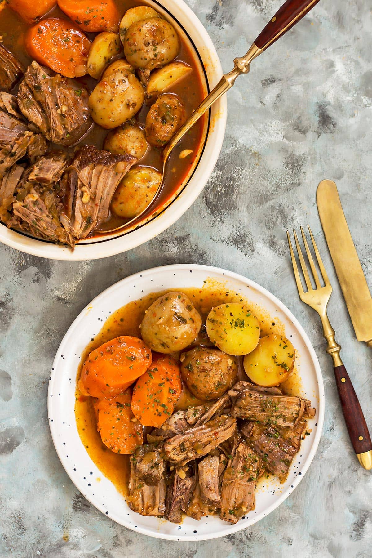 Plate and bowl of slow cooker pot roast with carrots and potatoes