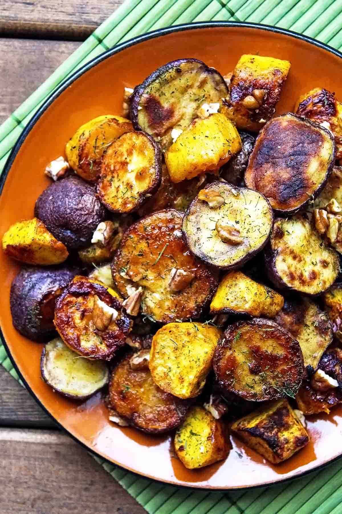 orange plate on green placemat with roasted potatoes and squash cubes