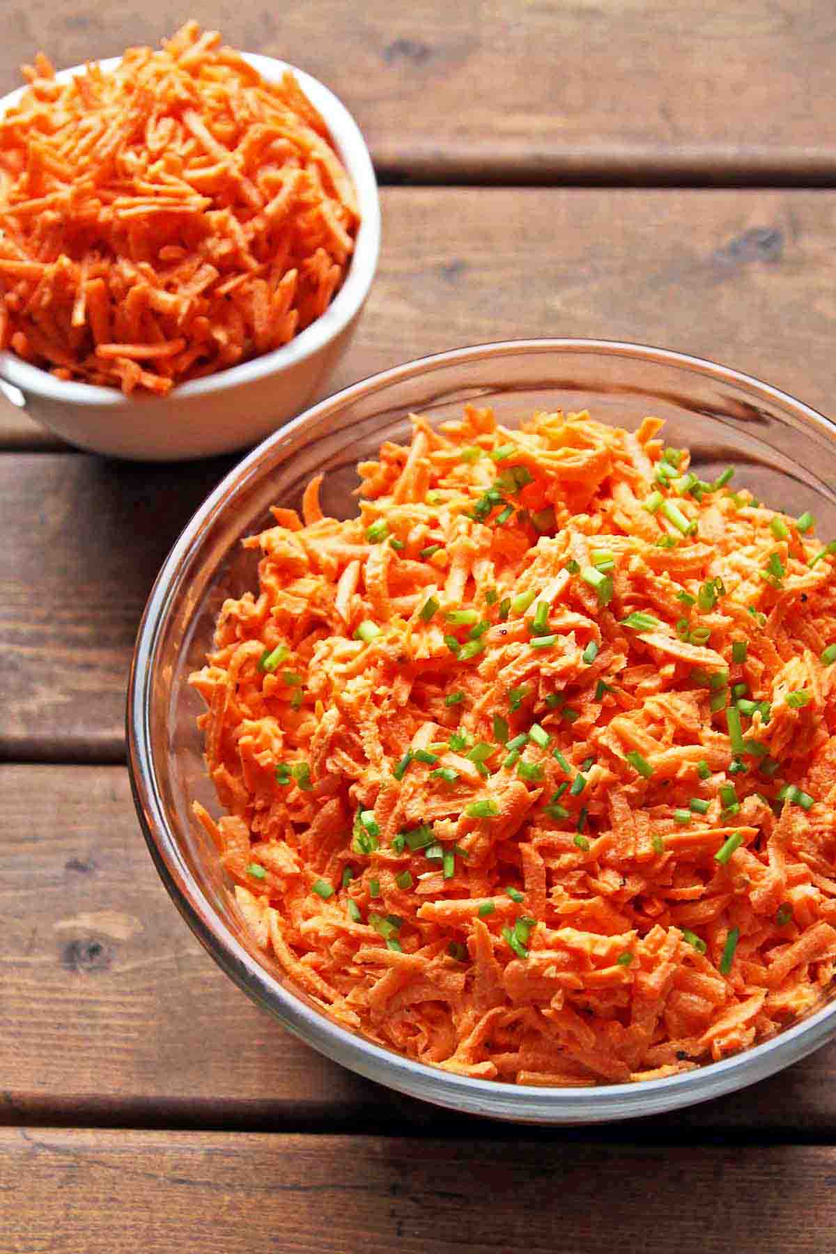 shredded carrot salad in large glass bowl and small white individual bowl