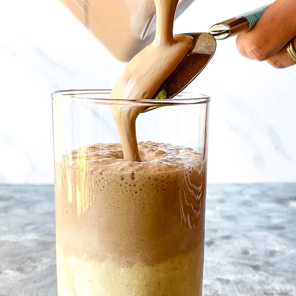 chocolate peanut butter smoothie pouring over back of a spoon into glass to create 2 layers