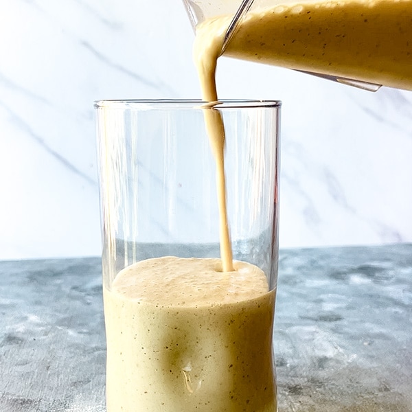 peanut butter protein smoothie pouring from blender into glass