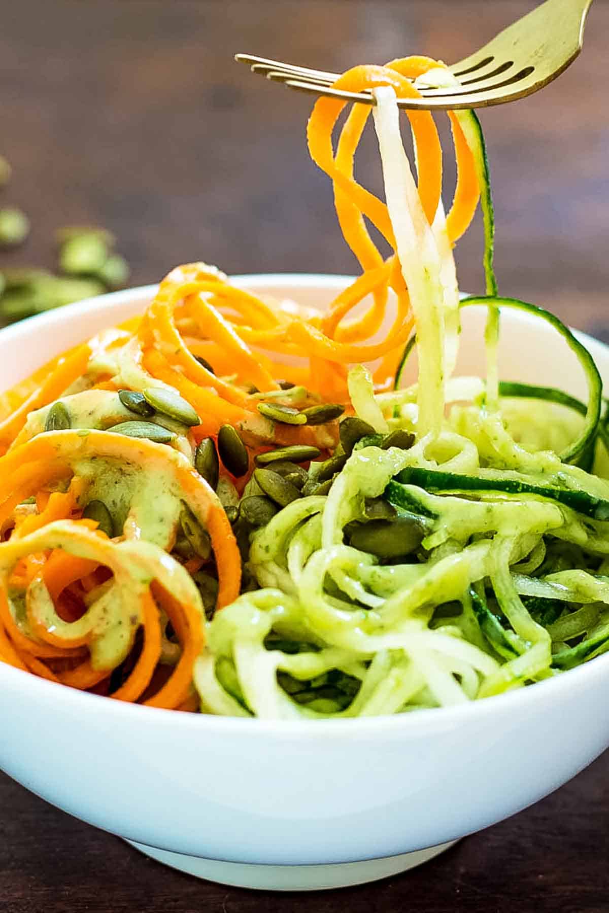 Fork over bowl of Carrot Cucumber and avocado salad