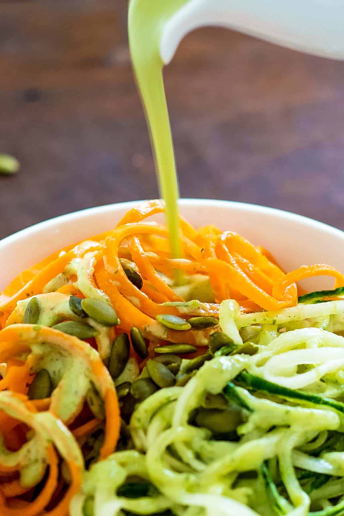 Carrot and cucumber salad with avocado dressing and pumpkin seed topping