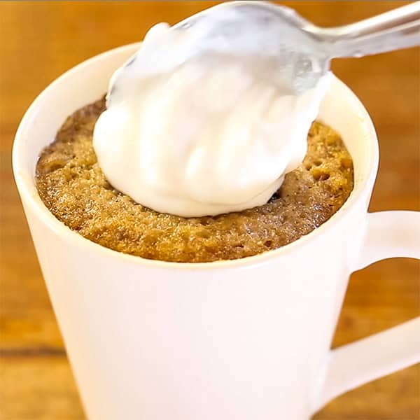 adding topping onto pumpkin spice mug cake