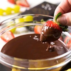 Strawberry being dipped in dark chocolate fondue