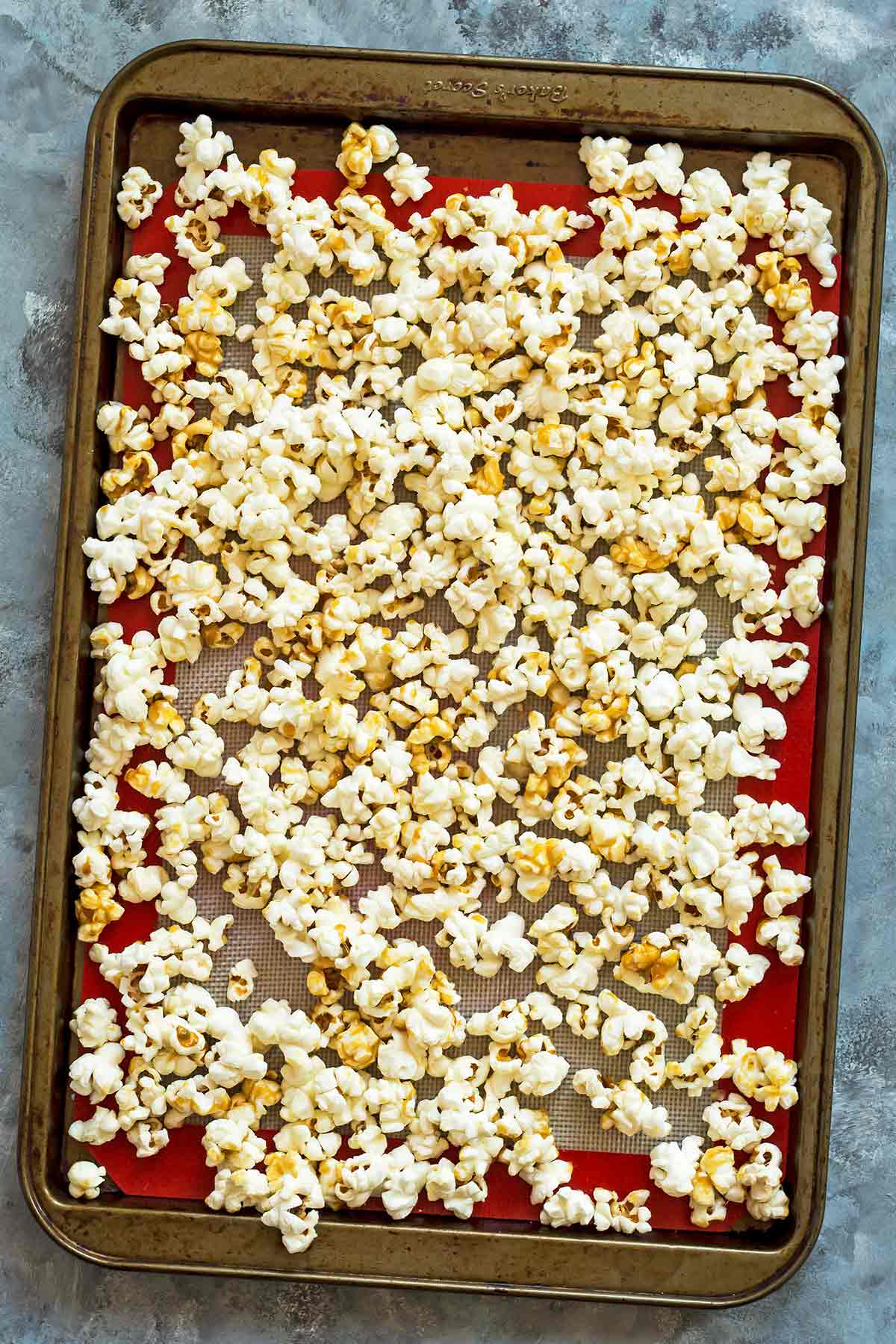 Caramel corn spread out on lined baking sheet