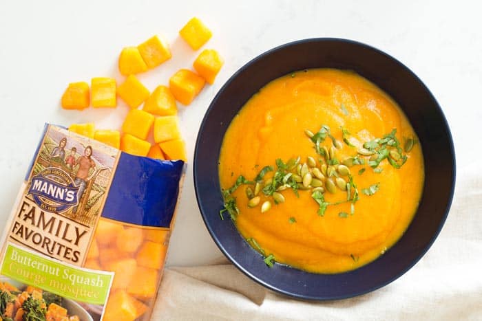 Bowl of butternut squash soup with a bag of cubed butternut squash beside