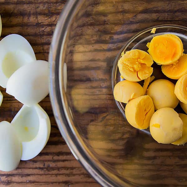 egg white halves on wooden counter egg yolks in glass bowl