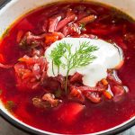 bowl of pink borscht with sour cream and dill topping