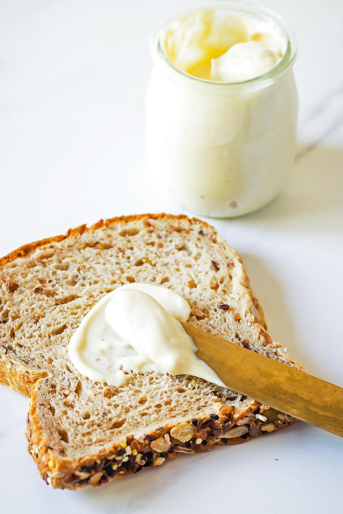 Knife spreading mayonnaise on bread slice