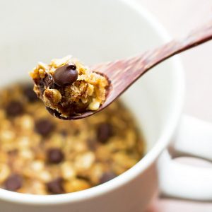 Spoonful of cookie with chocolate chip mug cookie in the back