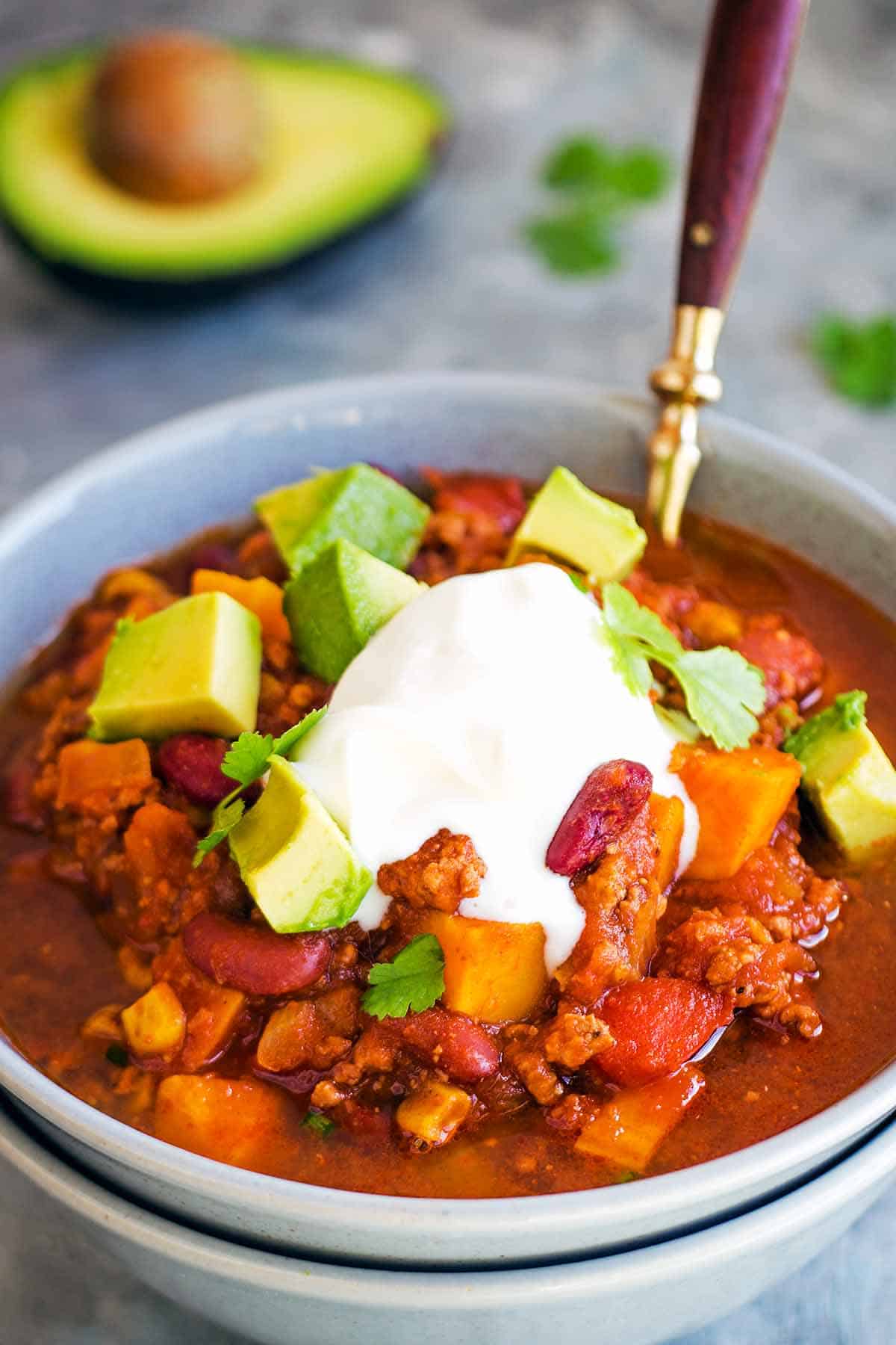 Sweet Potato Slow Cooker Chili in grey bowl with sour cream avocado topping