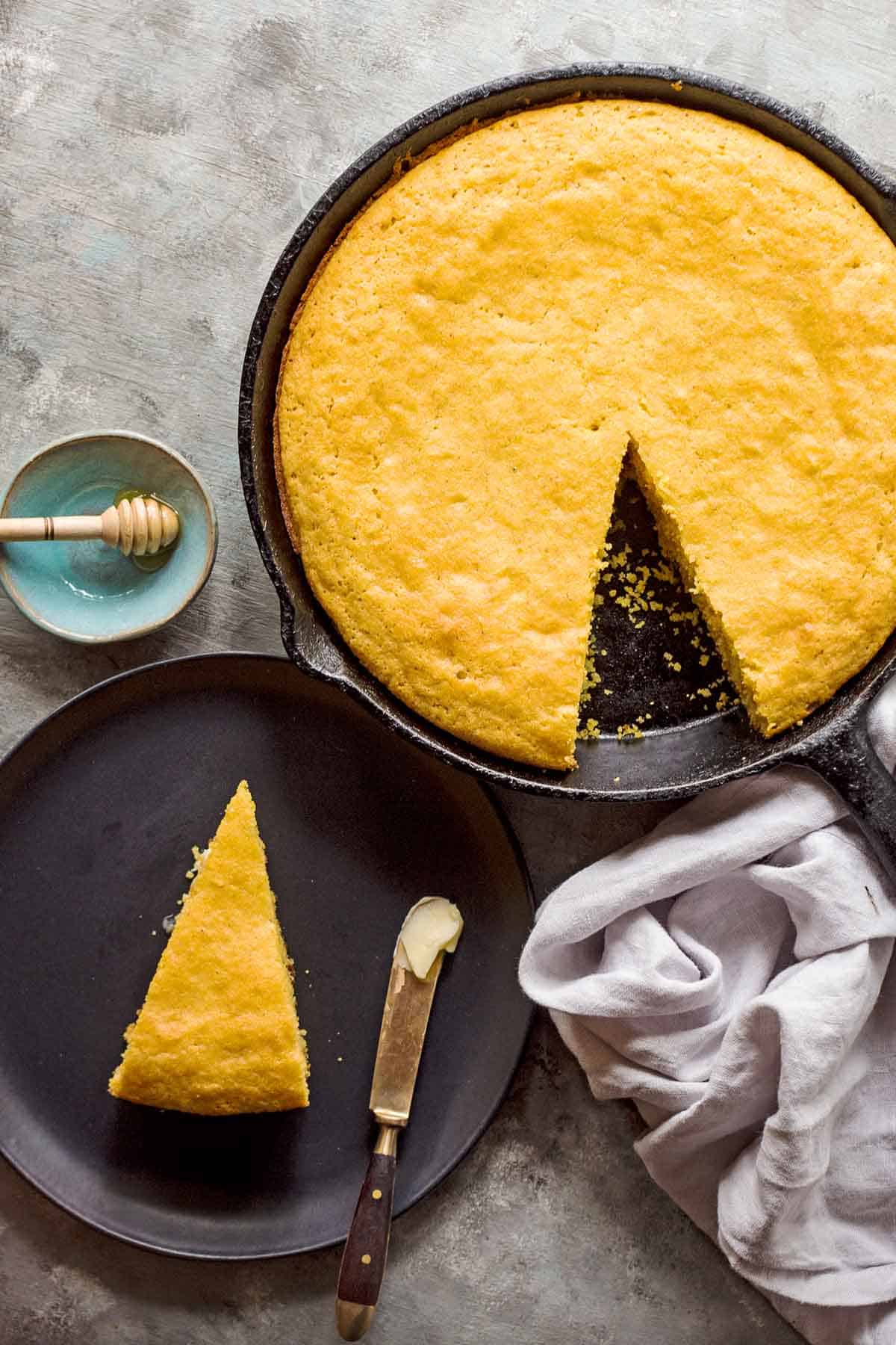 gluten free cornbread in cast iron skillet and one slice on black plate