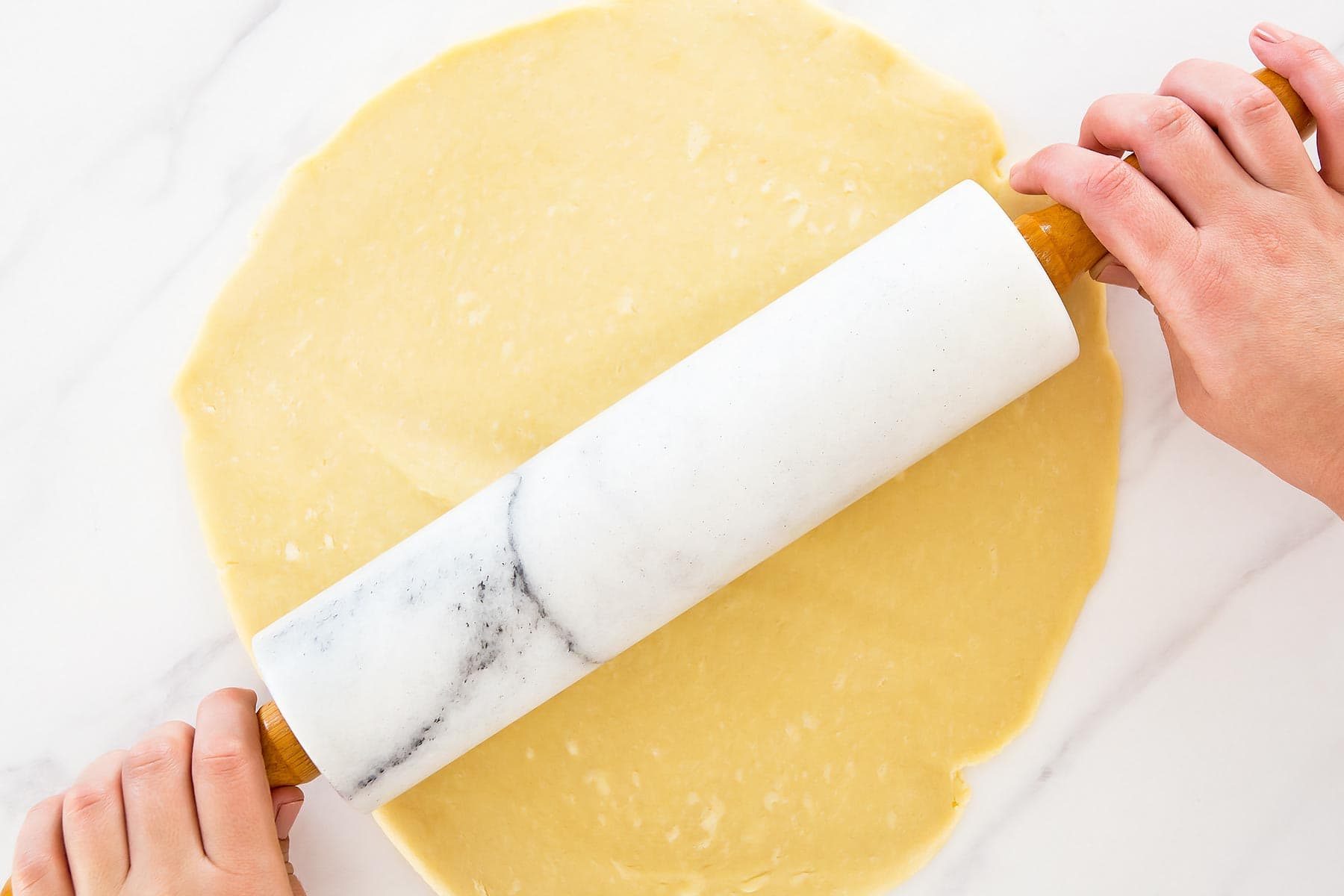 Marble rolling pin rolling out flaky pie dough