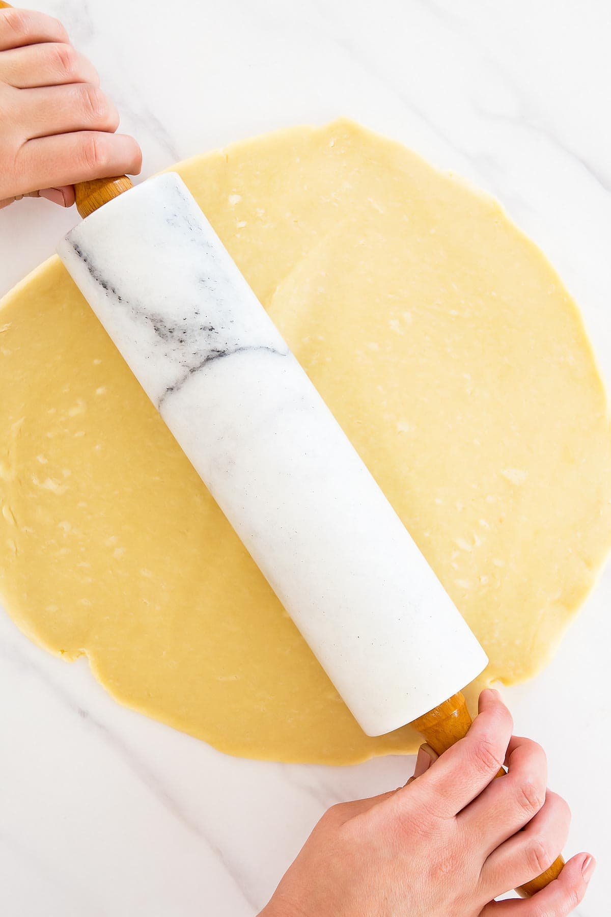 Marble rolling pin rolling out flaky pie dough