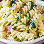 Spiral pasta with creamy bacon spinach sauce in bowl