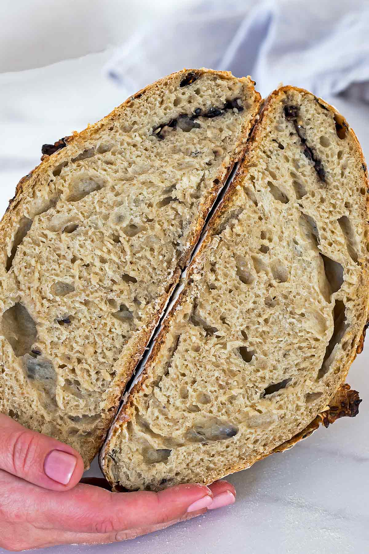 Hand holding homemade sourdough bread cut in half
