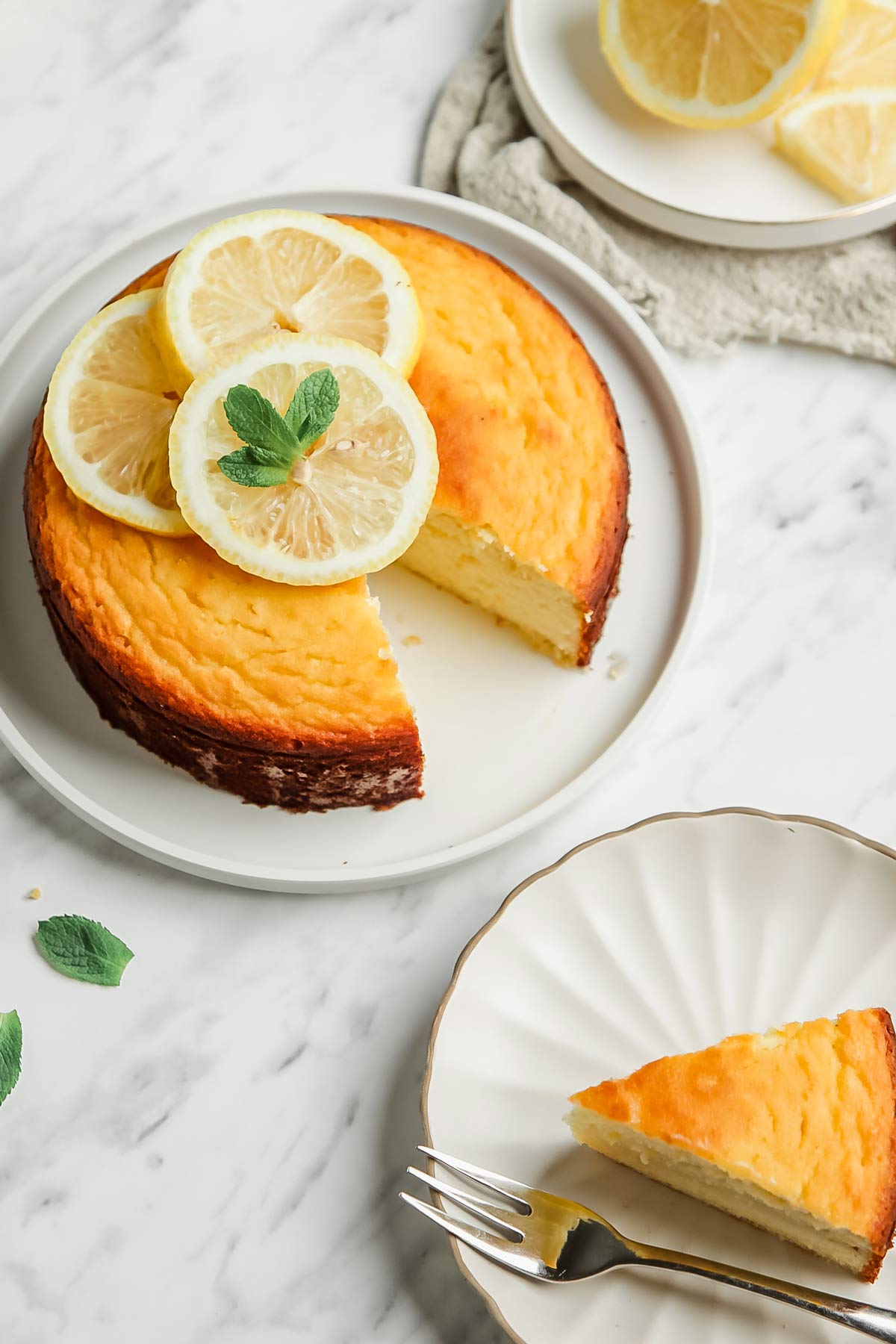 Whole lemon pound cake with 1 slice removed onto small white plate with fork
