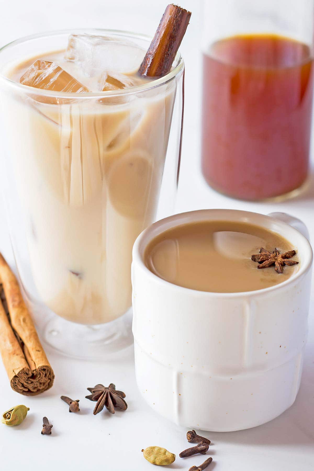 Iced chai in glass, hot chai in small white cup, and chai concentrate in bottle