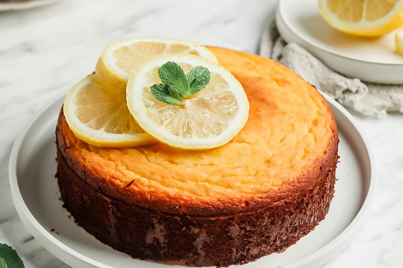 Paleo Lemon Cake on large white serving platter topped with 3 lemon slices
