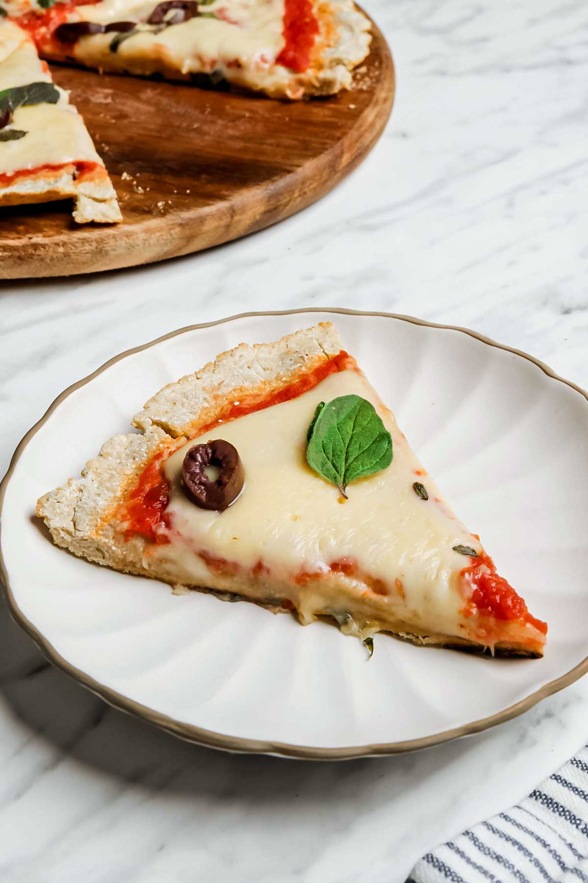 Slice of coconut flour crust pizza on small white plate