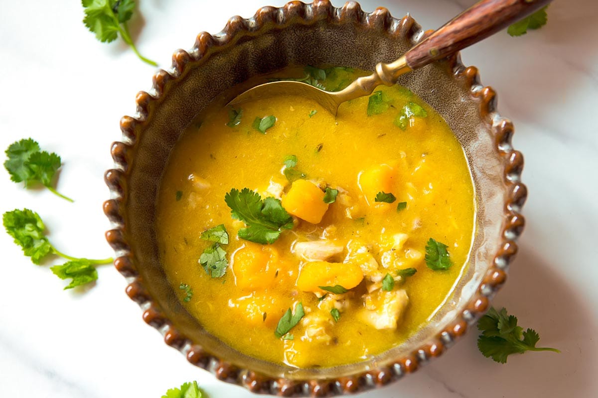 Pumpkin Chicken Soup in bowl with spoon and cilantro topping