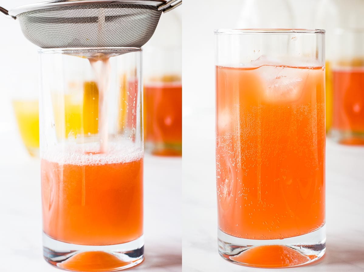 raspberry ginger kombucha pouring through strainer into glass of ice