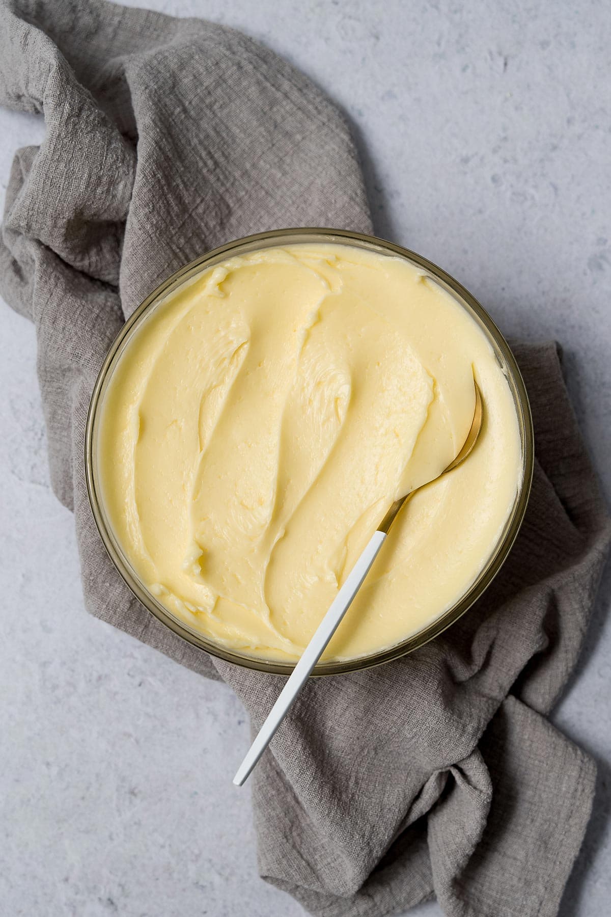 Reverse Swiss meringue buttercream in bowl with spoon on grey kitchen towel