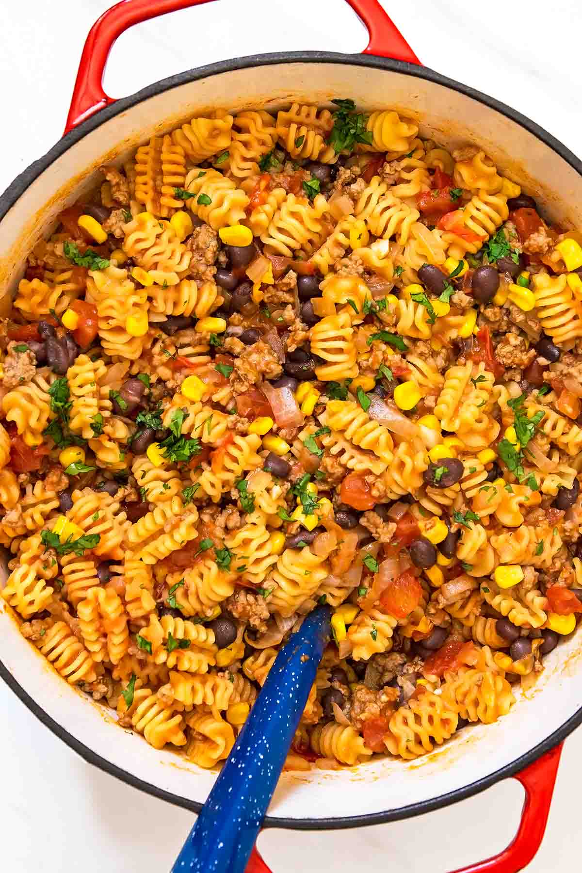 Easy Taco pasta in red dutch oven with blue serving ladle