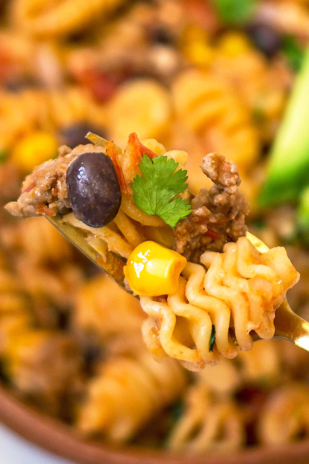taco pasta on fork with noodle black bean corn kernel and cilantro leaf