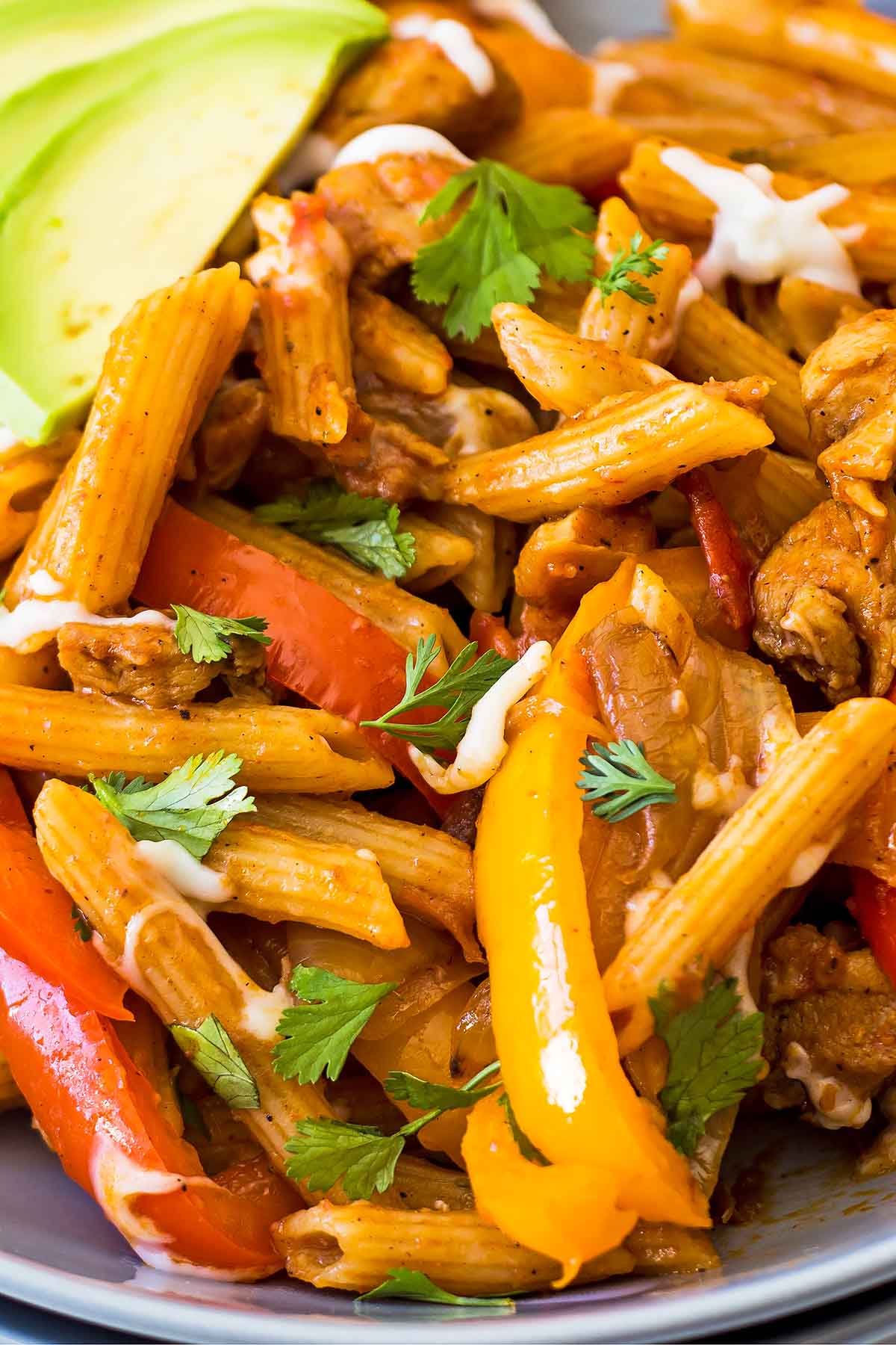 Fajita style pasta in serving bowl with sliced red and yellow bell pepper