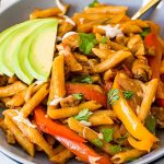 One pot chicken fajita pasta in grey serving bowl topped with cilantro, cheese, and avocado slices