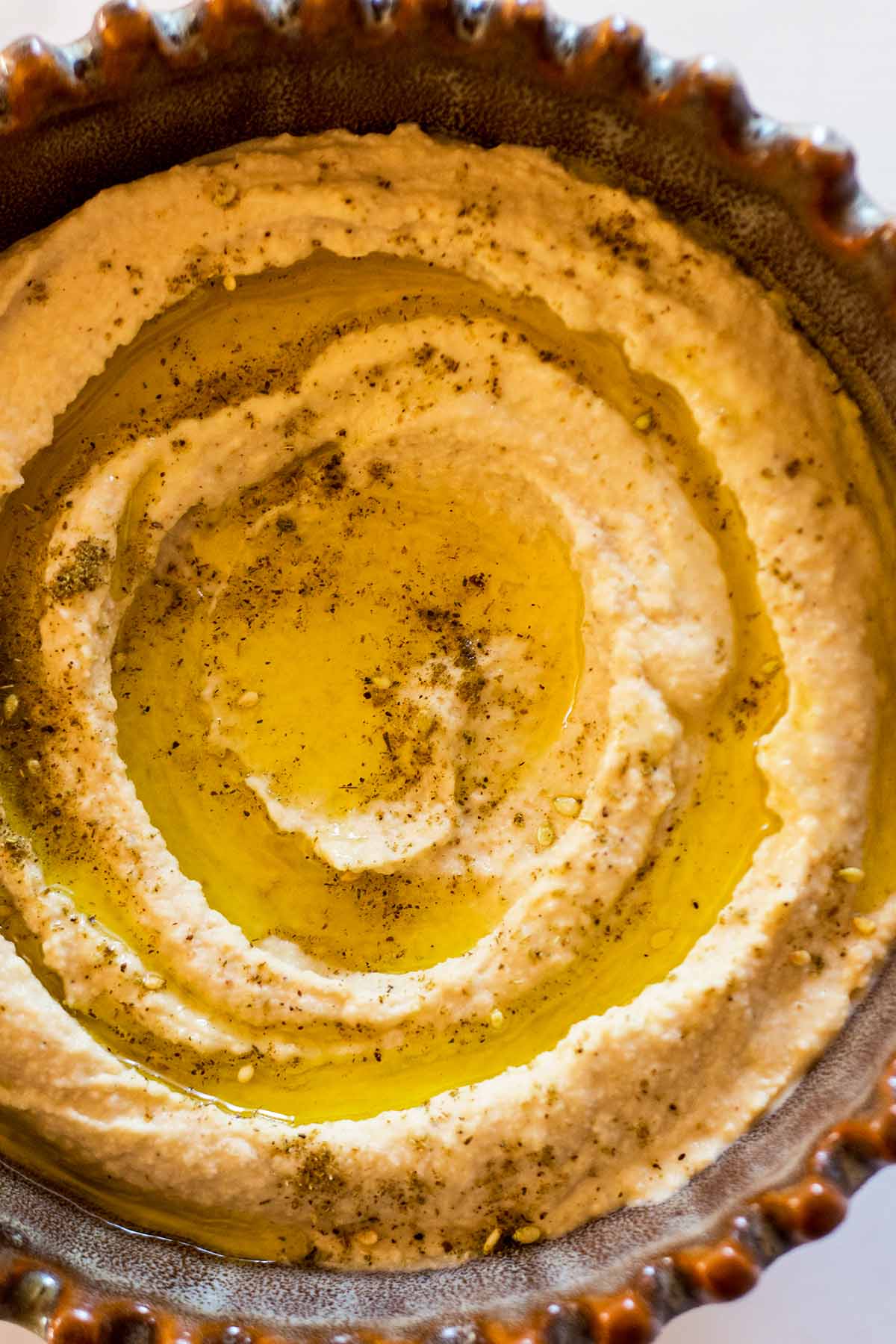 Easy hummus recipe served in brown bowl with scalloped edges