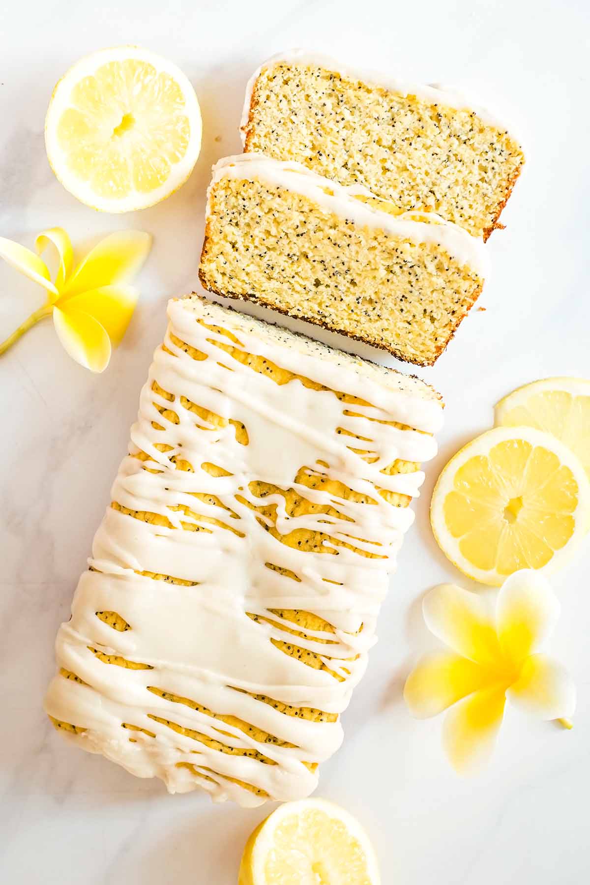 Healthy lemon loaf overhead shot with lemon slices and plumeria flowers