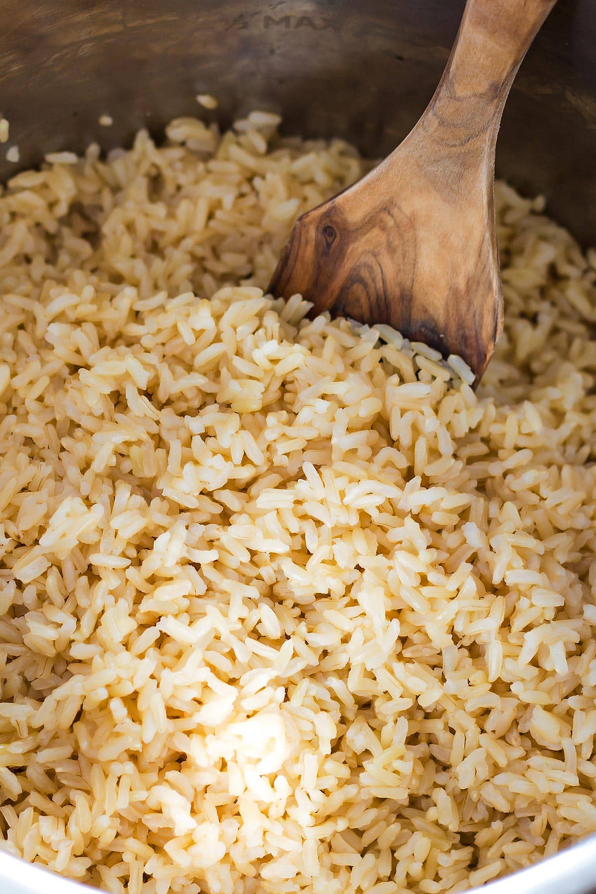 Cooked brown rice in Instant Pot with wooden spoon