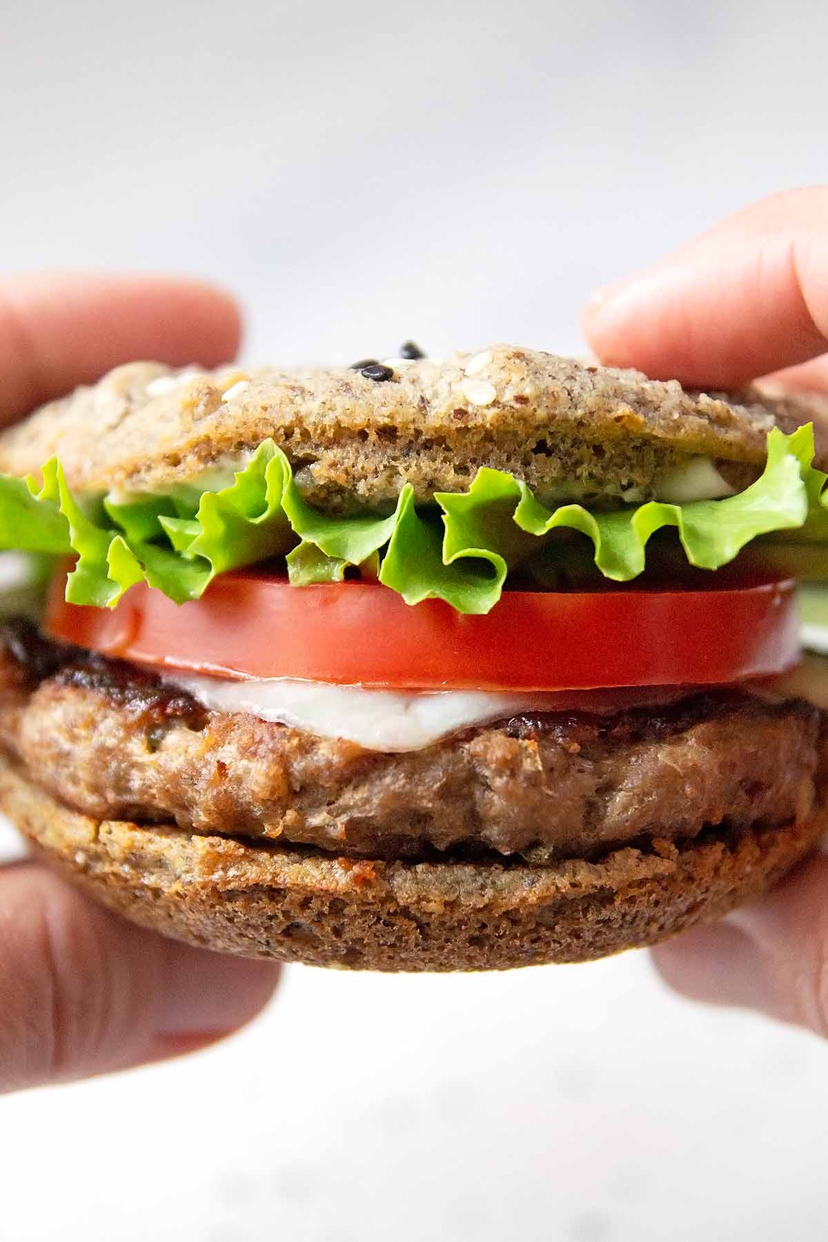 Keto Burger Buns made with coconut flour layered with hamburger patty, cheese, tomato and lettuce