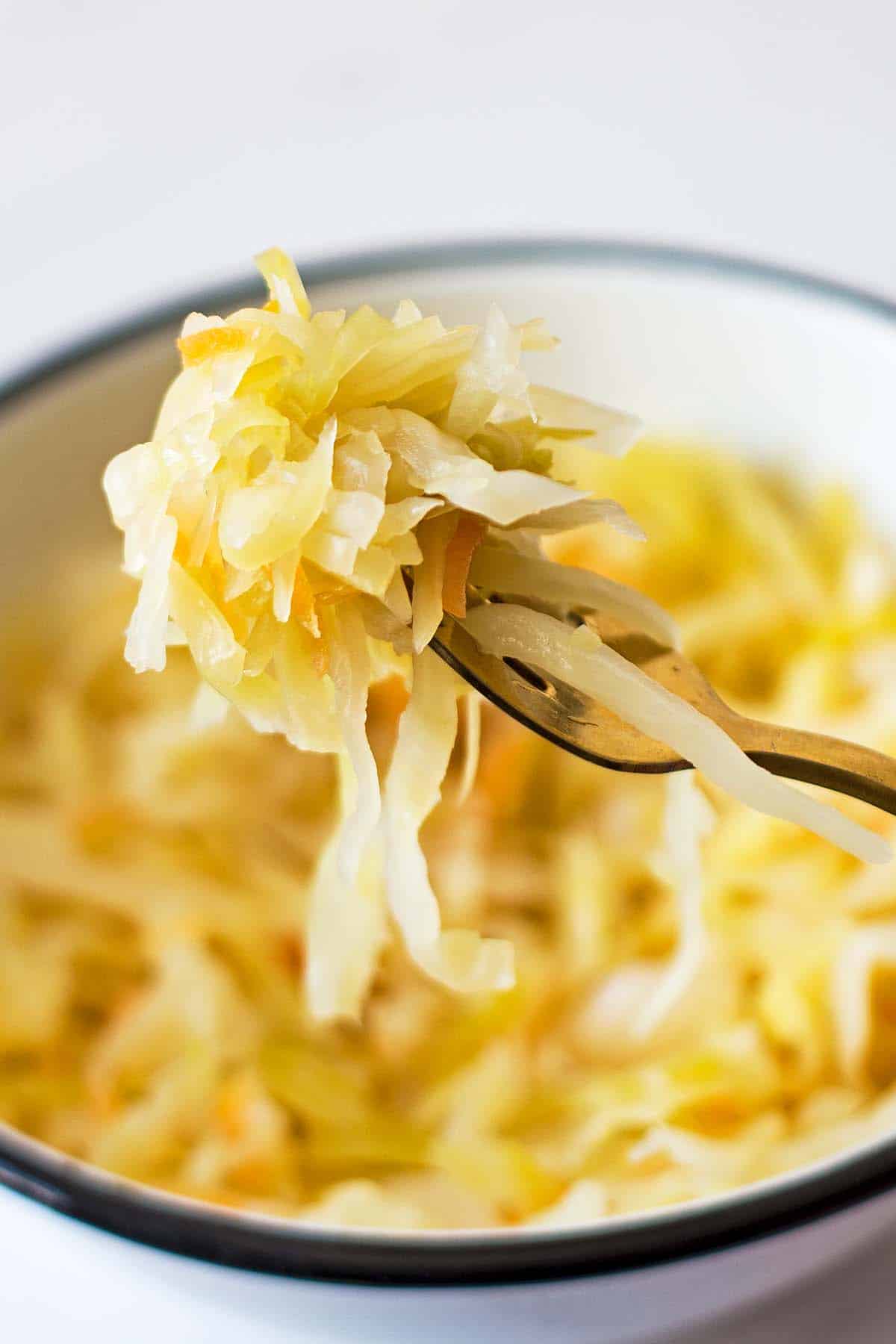 Sauerkraut fermented cabbage on a golden fork