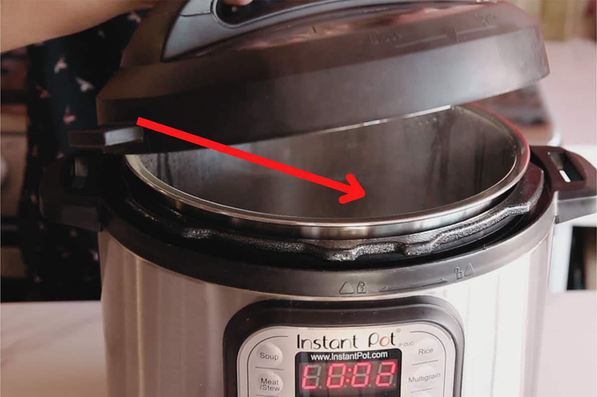 Instant pot lid with red arrow indicating direction to open away from body