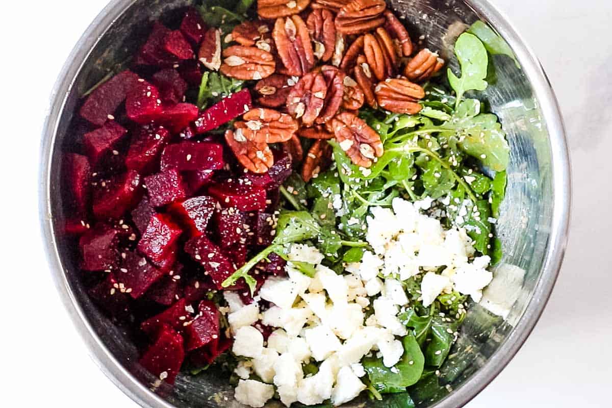 large stainless steel bowl with arugula, goat cheese, pecans, and beets