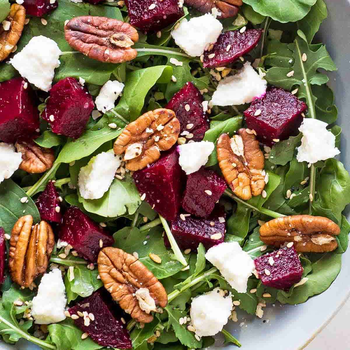 Bed of arugula leaves with cubed beets, goat cheese crumbles, pecan halves, and everything bagel seasoning
