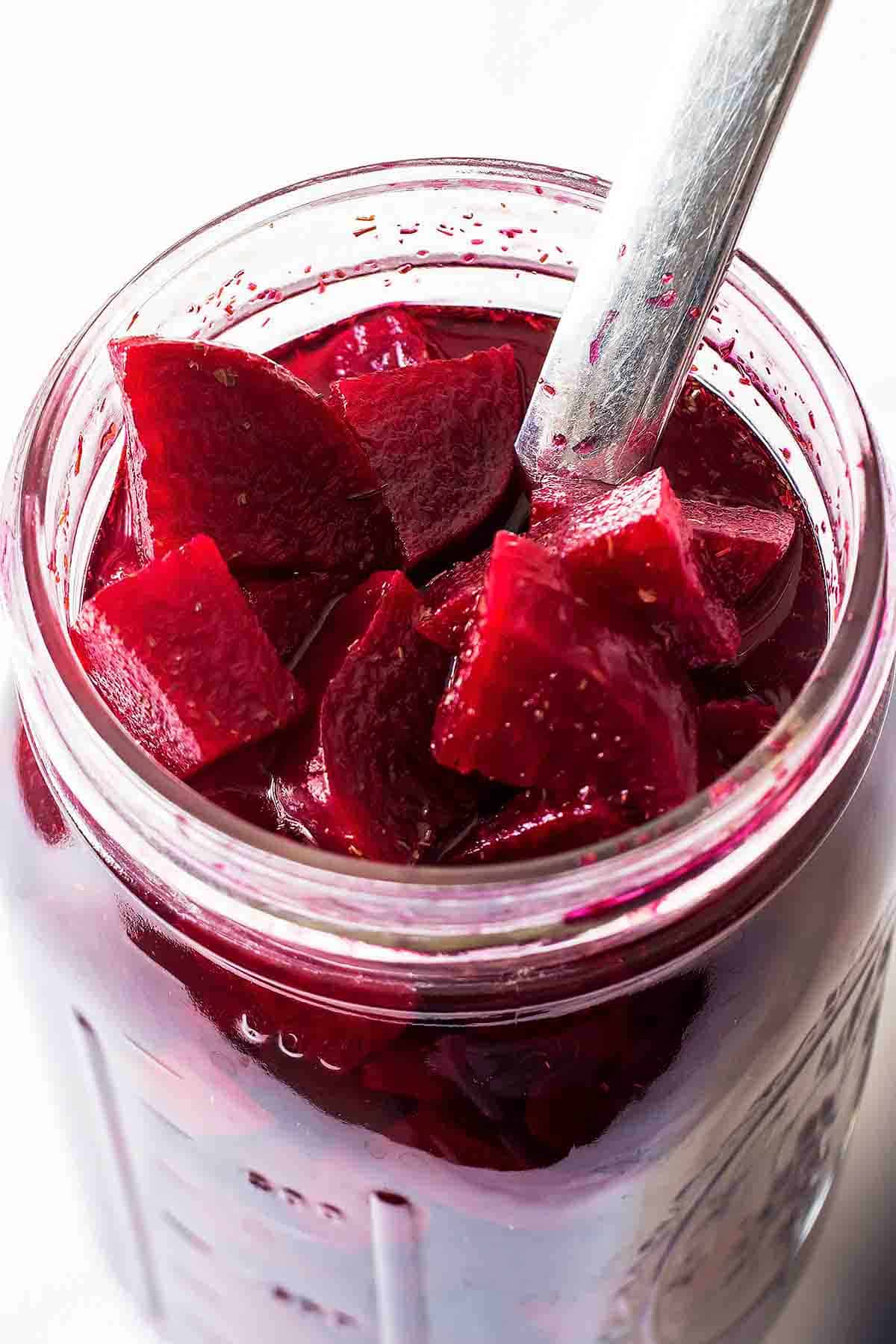 utensil lifting out quick pickled beet cubes from open mason jar
