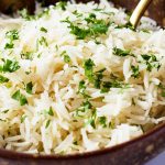 close up of cooked white rice in ceramic bowl with parsley topping