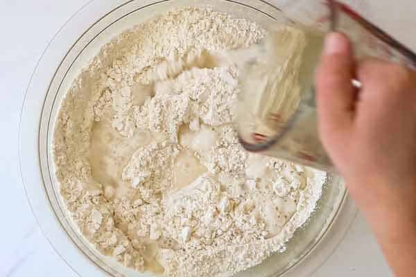 water pouring into bowl of flour yeast and salt