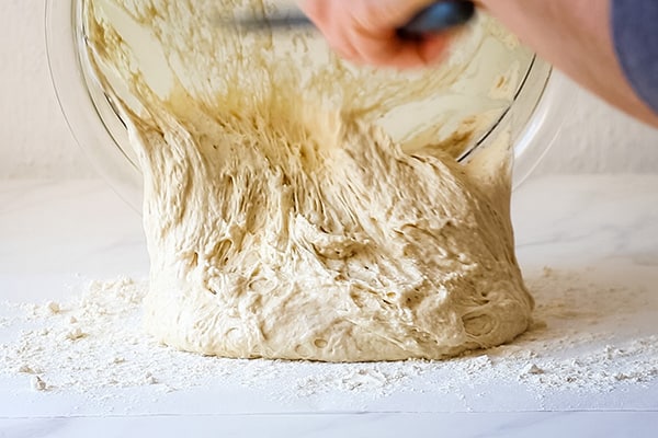 risen dough being turned out on a floured piece of parchment